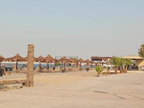einen Strand mit Tischen und Sonnenschirmen und dem Meer in der Unterkunft قرية النورس مكتب السعد in Ismailia