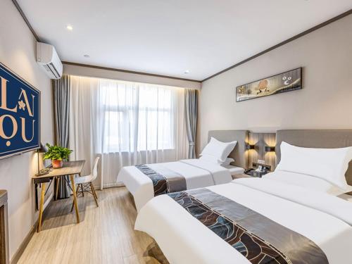 a hotel room with two beds and a desk at LanOu Hotel Langfang Gu'an Daxing Airport Wildlife Park in Langfang