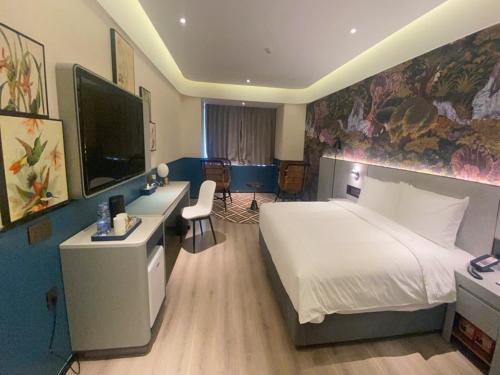 a hotel room with a large bed and a desk at LanOu Hotel Suqian Central Shopping Mall in Suqian