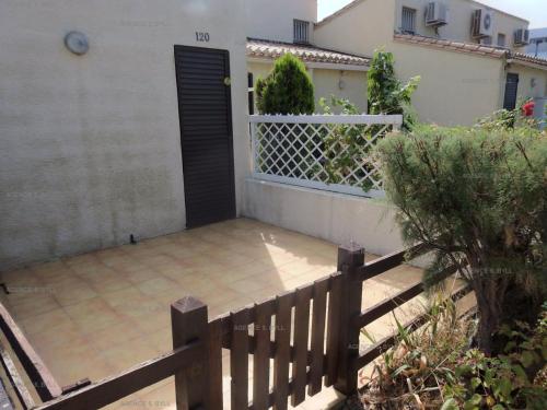 een huis met een hek en een veranda met een hek bij Résidence Héliovillage - Maisons & Villas pour 4 Personnes 944 - Naturiste in Cap d'Agde
