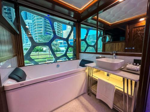 ドバイにあるOvernight Super Yacht - Orchidのバスルーム(バスタブ、シンク付)、窓が備わります。