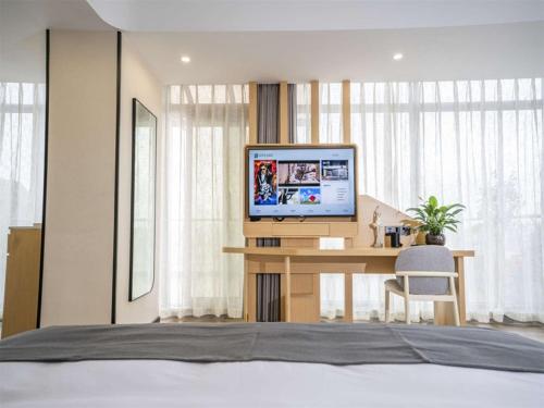 a bedroom with a desk with a television on it at Thank Inn Chain Wenshan Yanshan Qidu Plaza in Yanshan