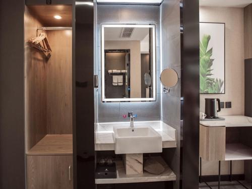 a bathroom with a sink and a mirror at Thank Inn Chain Hami Queen Sky Street in Hami