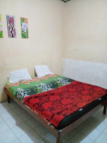 ein Bett in einem Zimmer mit einer roten Decke darauf in der Unterkunft Hotel Raya in Plaosan