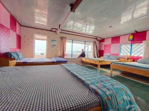 a room with three beds and a person sitting in it at Long Vĩ hotel - đảo Phú Quý in Cu Lao Thu
