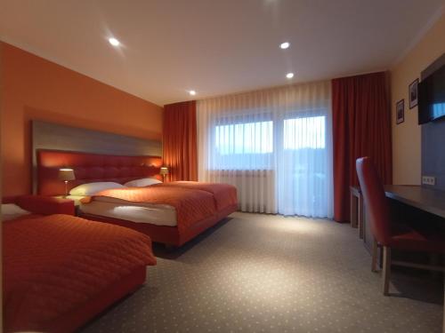 a hotel room with two beds and a desk at Hotel Waldblick in Donaueschingen