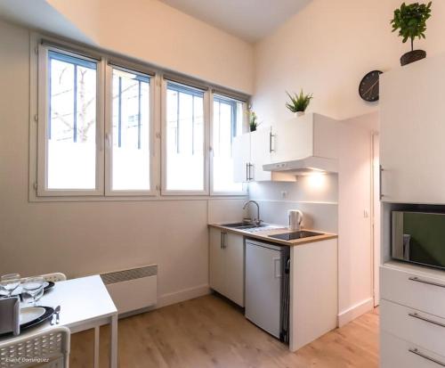 - une cuisine avec des appareils électroménagers blancs et des fenêtres dans l'établissement T1 Cosy prox. Gare , commerces et centre ville, à Villeurbanne