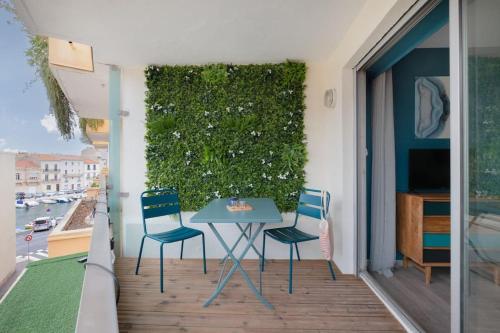 eine Terrasse mit Tisch und Stühlen auf einem Balkon in der Unterkunft L'Ecrin Bleu Parking-Clim-Cosy in Sète