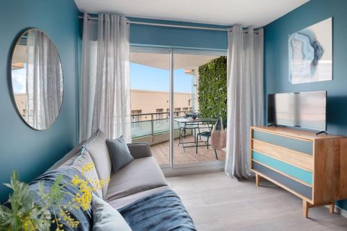 Il comprend un salon avec un canapé, une télévision et un balcon. dans l'établissement L'Ecrin Bleu Parking-Clim-Cosy, à Sète