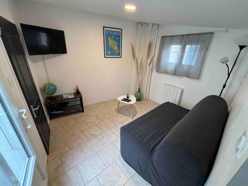 a living room with a bed and a television at Le Patio - Saint-Denis d’Oléron in Saint-Denis-dʼOléron