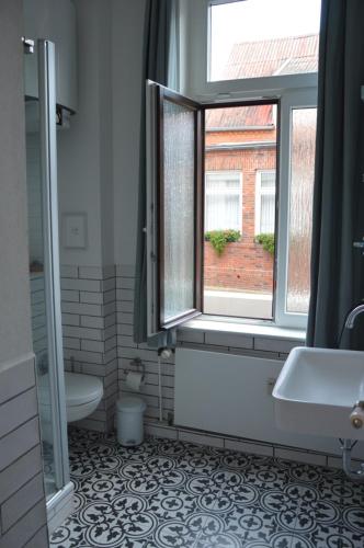 ein Bad mit einem Fenster, einem Waschbecken und einem WC in der Unterkunft Villa Scherz - stilvoll, zentral, ruhig, EG in Borkum