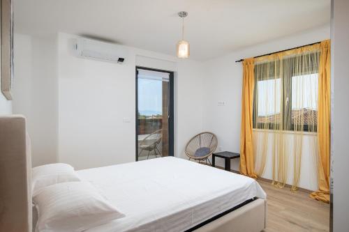 ein weißes Schlafzimmer mit einem Bett und einem Fenster in der Unterkunft Apartments Sara II in Ližnjan