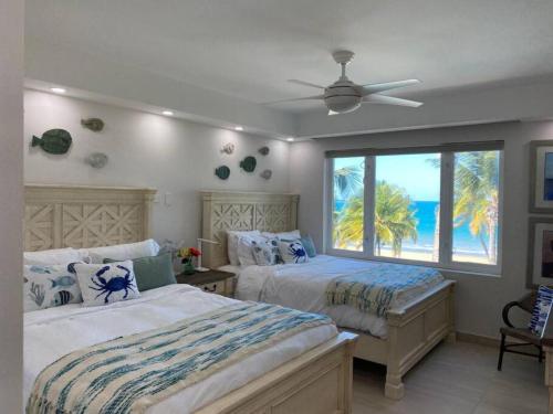 two beds in a bedroom with a view of the ocean at Luxury Beachfront 2 Bedroom at Wyndham Rio Mar, PR in Luquillo