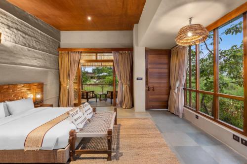 ein Schlafzimmer mit einem Bett und einem großen Fenster in der Unterkunft Sanctuary Resort, Chitwan National Park, Nepal in Chitwan