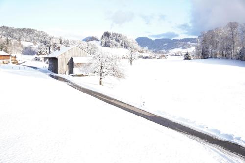 a snow covered field with a barn in the distance at Landwohnung in Lingenau