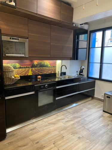 una cocina con electrodomésticos negros y armarios de madera en Chambre via Natina, en Saint-Germain-en-Laye