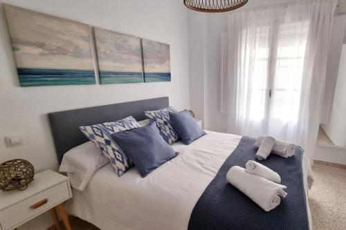 1 dormitorio con 1 cama con almohadas azules y blancas en www Casa Quili Cádiz com en Cádiz