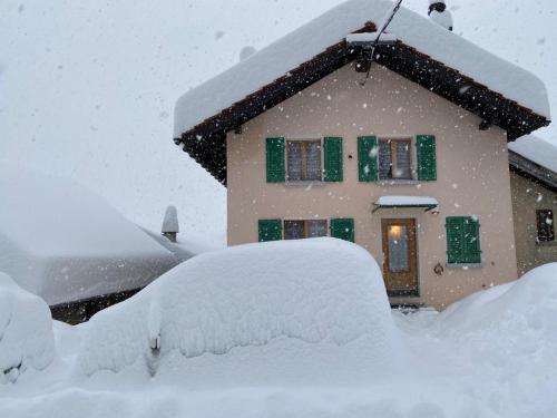 samochód pokryty śniegiem zaparkowany przed domem w obiekcie Chalet del Sole w mieście Quinto