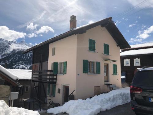 a house with green shuttered windows in the snow at Chalet del Sole in Quinto