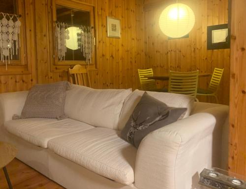 a white couch in a room with wooden walls at Chalet typique tout confort avec studio en dessous in Hérémence