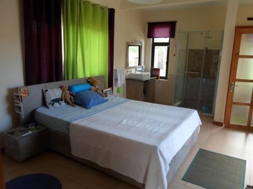 a bedroom with a large bed with two teddy bears on it at West Coast Villas in Tamarin