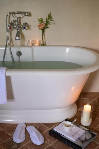 a white bath tub with a candle and flowers on it at Viesca Toscana Suites & Villas in Reggello