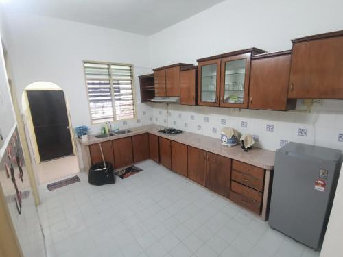 uma cozinha com armários de madeira e piso em azulejo branco em Home Sweet Home em Sungai Petani