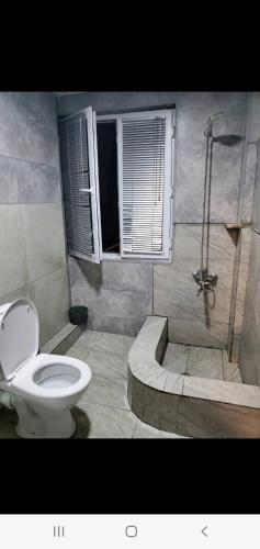 uma casa de banho com um WC e um chuveiro com uma janela em My home 1 em Kiketʼi