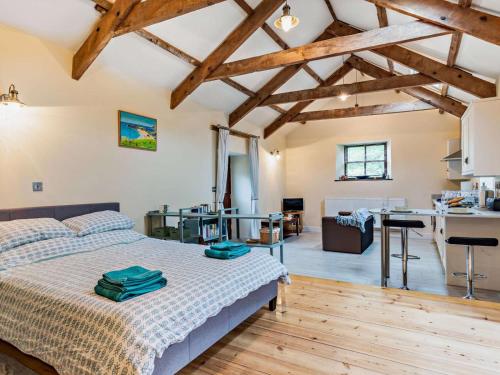 a bedroom with a bed in a room with wooden floors at Tiptoe Barn in Liskeard