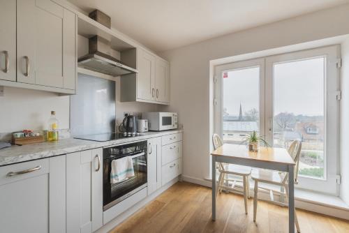 een keuken met witte kasten en een tafel en een raam bij Stylish 3 bedroom house with garage in Frome