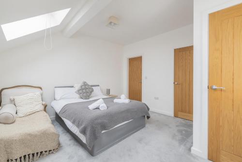 a white bedroom with a bed and a wooden door at Stylish 3 bedroom house with garage in Frome