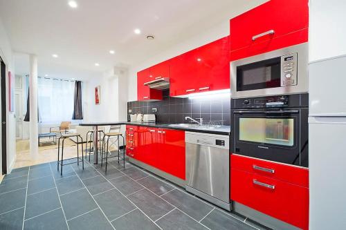 une cuisine avec des placards rouges et une table avec des chaises dans l'établissement Exceptionnel à Montmartre, à Paris