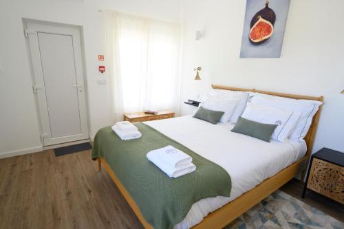 a bedroom with a large bed with towels on it at Ericeira TreeGarden in Ericeira