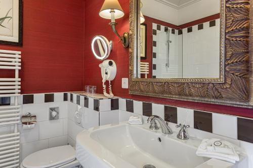 La salle de bains est pourvue d'un lavabo, de toilettes et d'un miroir. dans l'établissement Kipling Manotel, à Genève