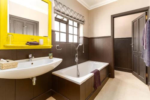 a bathroom with a white tub and a sink at Noordhoek Village Hotel in Noordhoek