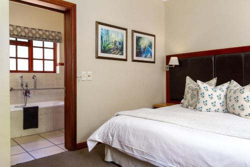 a bedroom with a bed and a bath tub at Noordhoek Village Hotel in Noordhoek
