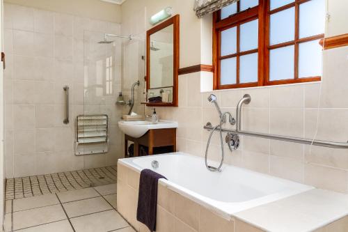 a bathroom with a tub and a sink at Noordhoek Village Hotel in Noordhoek