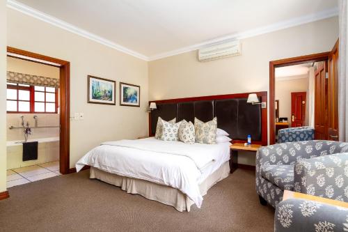 a hotel room with a bed and a bathroom at Noordhoek Village Hotel in Noordhoek