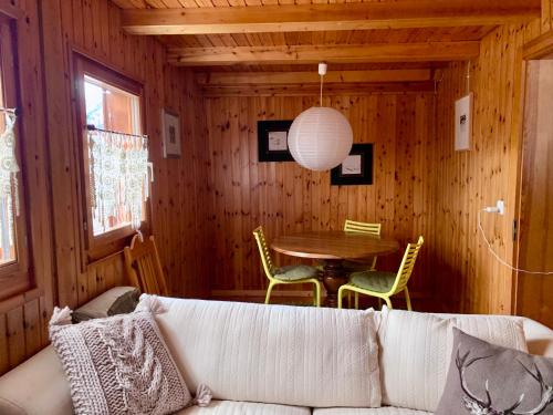 uma sala de estar com um sofá e uma mesa em Chalet typique tout confort avec studio en dessous em Hérémence