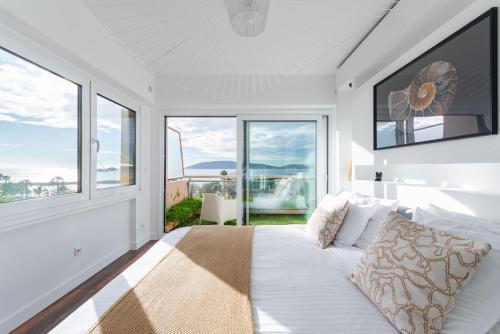 - une chambre blanche avec un lit et de grandes fenêtres dans l'établissement Grand Appartement Balcon Vue Mer 20m Plage Mourillon, à Toulon