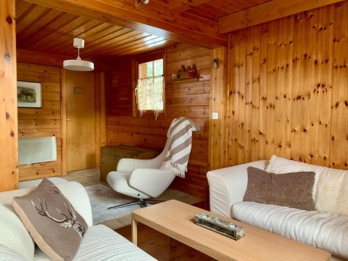 a living room with wooden walls and white furniture at Chalet typique tout confort avec studio en dessous in Hérémence