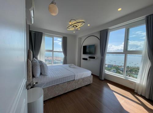 a bedroom with a bed and large windows at Smile Apartment in Ha Long