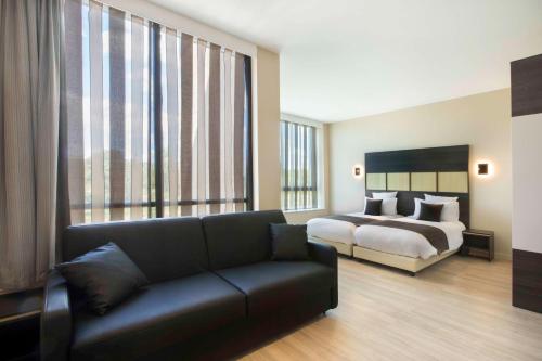 - un salon avec un lit et un canapé dans l'établissement Best Western Plus Hôtel Escapade Senlis, à Senlis