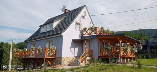 a white house with balconies and plants on it at Sowi Dom - Jugów in Jugów
