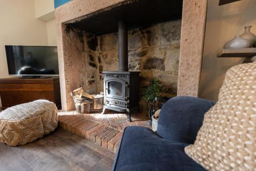 a living room with a fireplace and a blue couch at Rose Cottage by Coast & Country Stays in Beadnell