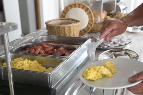 a person holding a spatula over a tray of food at Hotel Rezi in Parga