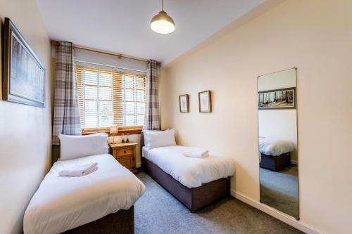 a bedroom with two beds and a mirror at Garden Flat West Kincaple House in St. Andrews