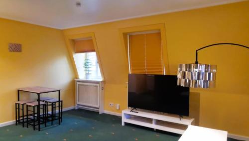 ein Wohnzimmer mit einem Flachbild-TV an einer gelben Wand in der Unterkunft Schöne Mindeltal Wohnung - Legoland - Skylinepark in Thannhausen