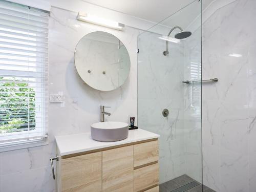 uma casa de banho branca com um lavatório e um espelho em Moonya Avocado Farm Cottage - with early check-in em Mount Tamborine