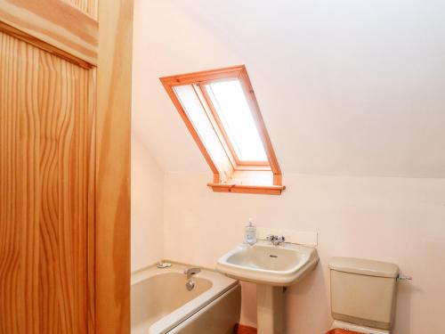 a bathroom with a sink and a toilet and a window at Ar Dachaigh in Paible